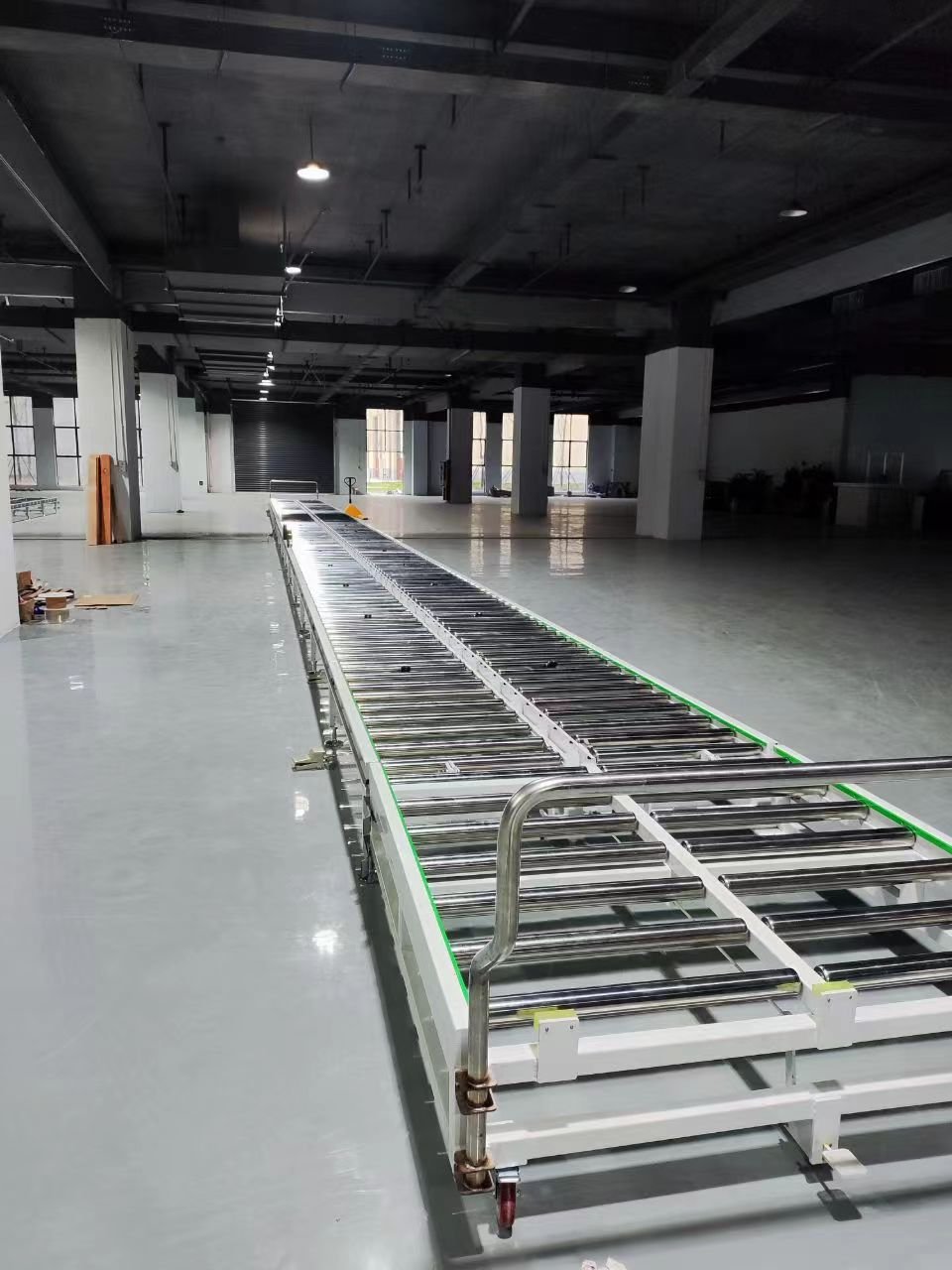 Long industrial roller conveyor line installed in factory for pallet transfer and automated material handling system