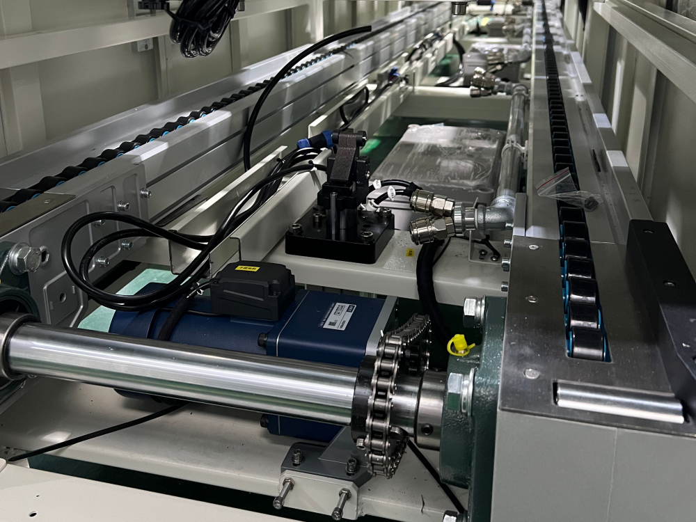 Close-up of pallet conveyor drive system showing motor, chain transmission, and internal mechanical components